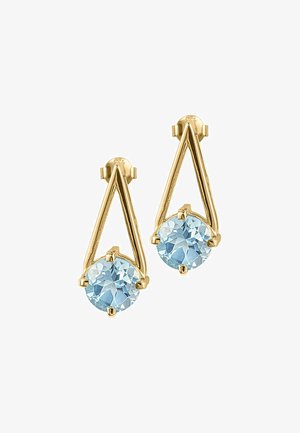 Boucles d'oreilles dorées avec un design géométrique, présentant une pierre précieuse ronde de couleur bleu clair suspendue à un cadre triangulaire.