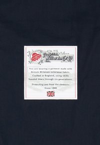 Granatowy materiał z wplecioną etykietą w białym kolorze, na której znajduje się tekst o British Millerain. Zawiera brytyjską flagę oraz dekoracyjny bord. 