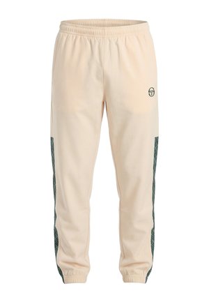 Pantalones jogger beige con cintura elástica, paneles laterales oscuros con estampado y puños elásticos, con un pequeño logotipo circular en la parte superior del muslo izquierdo.