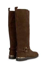 Stivali alti in suede marrone con suola piatta, dotati di un dettaglio decorativo a nodo e accenti metallici sul tacco.