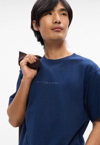 Σκούρο μπλε βαμβακερή μπλούζα τύπου t-shirt με στρογγυλή λαιμόκοψη και κοντά μανίκια, που διαθέτει μια διακριτική εκτύπωση λογότυπου "SCOTCH & SODA" στο στήθος.