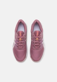 Baskets de sport violettes avec une tige en maille texturée, semelle en caoutchouc et rayures blanches contrastées. Comprend des lacets et un col rembourré.