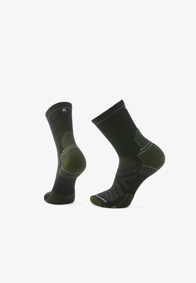 Dark green and black hiking socks with ribbed texture, reinforced heel, and toe, featuring a striped pattern on the ankle.