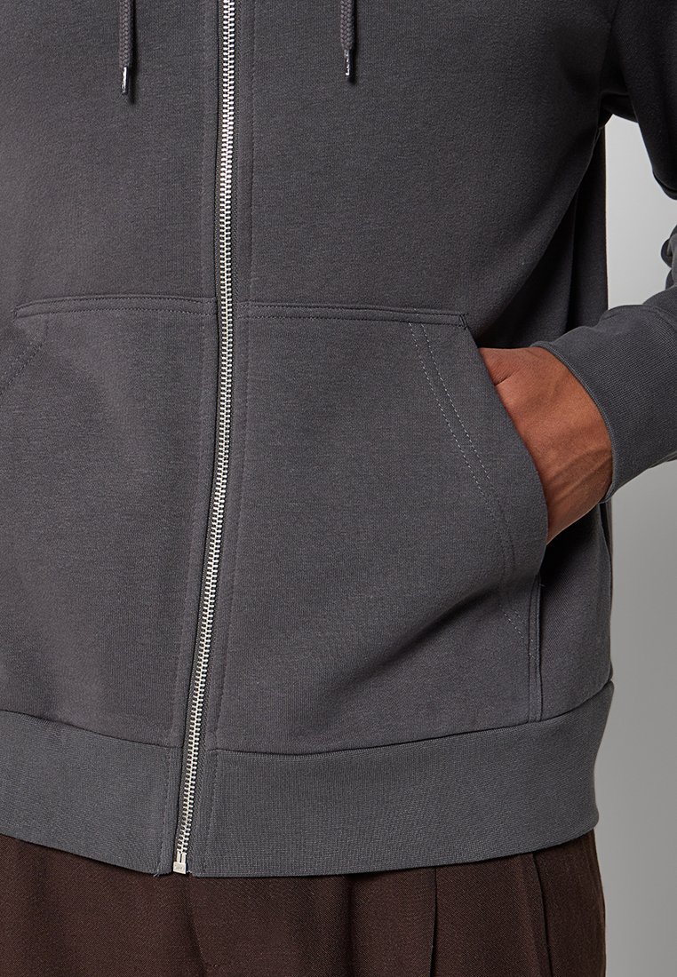 Ciemnoszara bluza zapinana na zamek z mieszanki bawełny, z metalowym suwakiem, przednimi kieszeniami oraz ściągaczami u dołu i na mankietach.