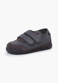 Scarpa grigio scuro realizzata in materiale sintetico liscio con dettagli in camoscio. Presenta due fascette in Velcro e una suola in gomma testurizzata.