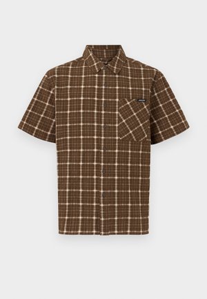 Chemise marron à manches courtes avec un motif à carreaux blanc et beige, col pointu et poche poitrine avec une petite étiquette noire.