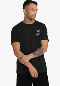 Zwarte korte mouwen T-shirt van katoen, met een wit vierkant logo op de linkerborst en een klassieke ronde halslijn.