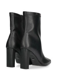 Botas de tobillo de cuero negro con un acabado texturizado, puntera redondeada y un tacón ancho alto; cuentan con una cremallera lateral para facilitar su uso.