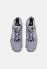 Scarpe da atletica di colore viola chiaro con tomaia in rete, lacci blu scuro e accenti testurizzati. Presentano un colletto imbottito e una suola a contrasto.
