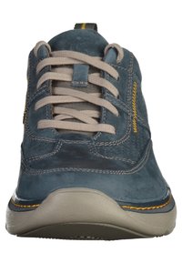 Sneaker blu in suede con lacci grigi, collo imbottito e dettagli in cucitura gialla. Presenta una suola in gomma testurizzata con una forma arrotondata.