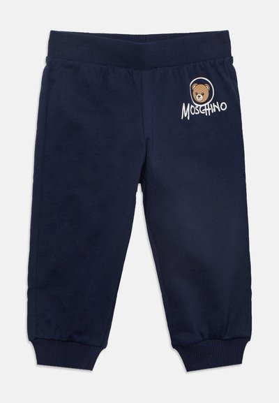 Pantalon de survêtement bleu marine pour enfants avec taille et poignets côtelés, avec un logo d'ours en peluche et le texte "Moschino" sur la partie supérieure de la jambe gauche.