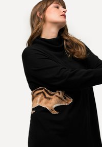 Maglione nero lavorato a maglia con collo a pipistrello. Presenta un design di scoiattolo ricamato in tonalità beige e marrone sul lato, che mette in mostra dettagli e texture raffinate.
