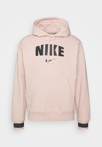 Sudadera Nike de color rosa claro con un gran logo negro "NIKE", cordones, bolsillo frontal y detalles en negro en las mangas.