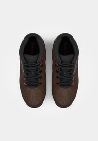 Pair of brown and black hiking boots with padded collars and black laces, viewed from above on a white background.