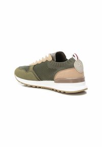 Zapatilla deportiva verde y beige con materiales de malla y ante, acentos texturizados, cuello acolchado, suela intermedia blanca y logo en el talón.