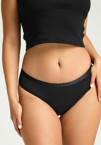 Culotte en coton noir avec une texture lisse et une large ceinture brillante. Façonnée pour le confort avec un design taille mi-haute.