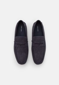 Mocassins en suède bleu marine foncé avec un bout arrondi, une sangle frontale et des détails de couture subtils. Semelle intérieure rembourrée pour le confort.