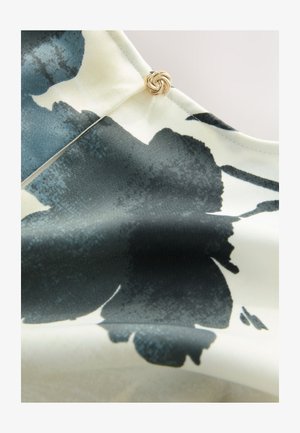 Blomstret stof med mørkeblå og sort abstrakt mønster på en cremefarvet baggrund. Indeholder en dekorativ guldknytteknap-detalje.