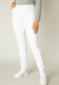Witte denim skinny jeans met een hoge taille, voorzakken en een gladde textuur. Gecombineerd met witte platform sneakers.