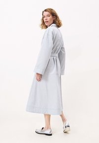 Blau-weißer gestreifter langer Bademantel mit weiten Ärmeln, tailliert, kombiniert mit silbernen Loafers, die ein fließendes, strukturiertes Design aufweisen.