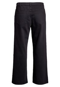 Mustat löysät farkut, joissa on teksturoitu kangas, viisi taskua ja vetoketjukiinnitys. Vyötäröosassa on vyölenkit ja ompeluyksityiskohtia.