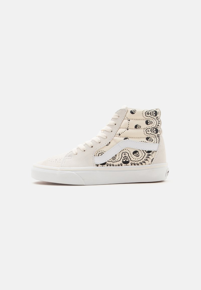 Beiger High-Top-Sneaker mit weißem Seitenstreifen, schwarzem Totenkopf- und Paisley-Muster am Knöchel und an der Ferse sowie weißer Gummisohle.