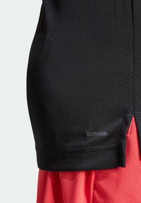 Crni sportski top s perforiranom teksturom i crvenim akcentima, s ClimaCool oznakom na rubu, dizajniran za prozračnost i udobnost.