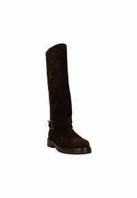 Botte en suede marron, hauteur genou, avec un bout arrondi, une semelle plate et une sangle décorative à boucle près de la cheville. Texture lisse avec une finition mate.