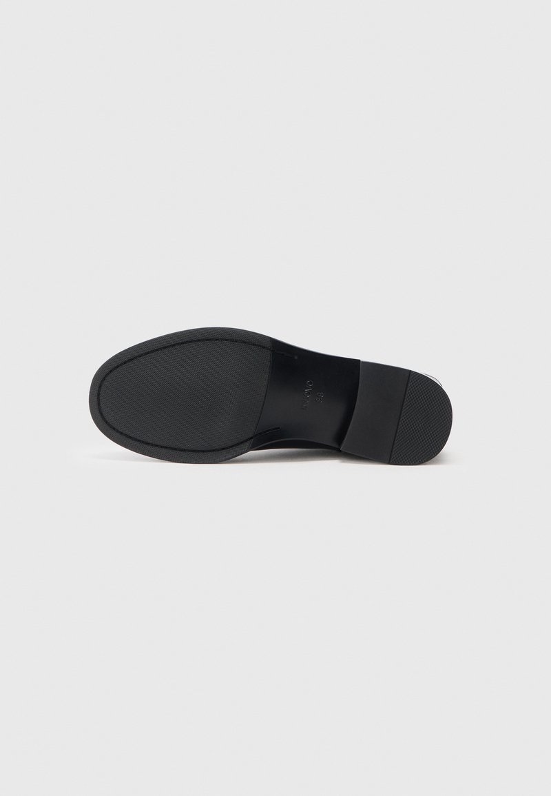 Semelle de chaussure en cuir noir avec une adhérence texturée en caoutchouc, présentant un bord lisse et arrondi ainsi qu'un design minimaliste pour la stabilité.