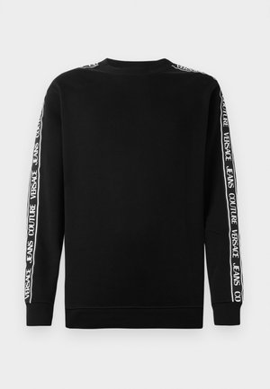 Sweatshirt preto com mangas longas e com a marcação em texto branco na vertical ao longo dos lados. Punhos e gola canelados. Textura de tecido suave.