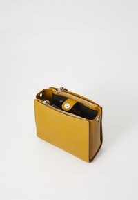 Borsa a mano in pelle gialla con superficie testurizzata, dotata di chiusura zip sulla parte superiore e chiusura a scatto. Interno nero. Forma rettangolare.