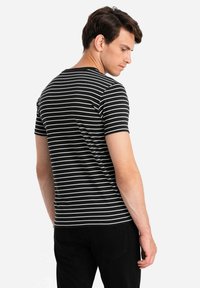 Černobílé pruhované tričko s krátkým rukávem. Měkce tkaná látka, kulatý výstřih, přiléhavý střih a ploché švy na ramenou.