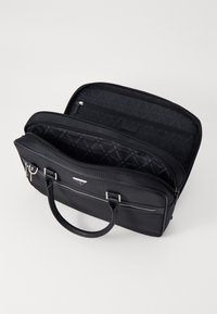 Borsa sintetica nera con scomparti a doppia cerniera, manici piatti, motivo a logo all'interno e finiture in metallo argentato.