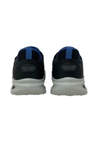 Sneakers slip-on in rete nera con accenti blu, dotati di una suola bianca leggera e un pannello posteriore testurizzato con dettaglio del logo.