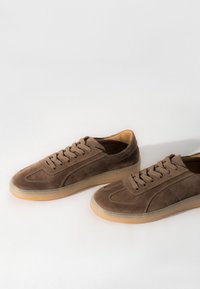 Braune Wildledersneaker mit runden Zehen, gesteppten Akzenten und hellbraunen Schnürsenkeln. Verfügt über eine transparente Gummisohle und ein weiches Innenfutter.