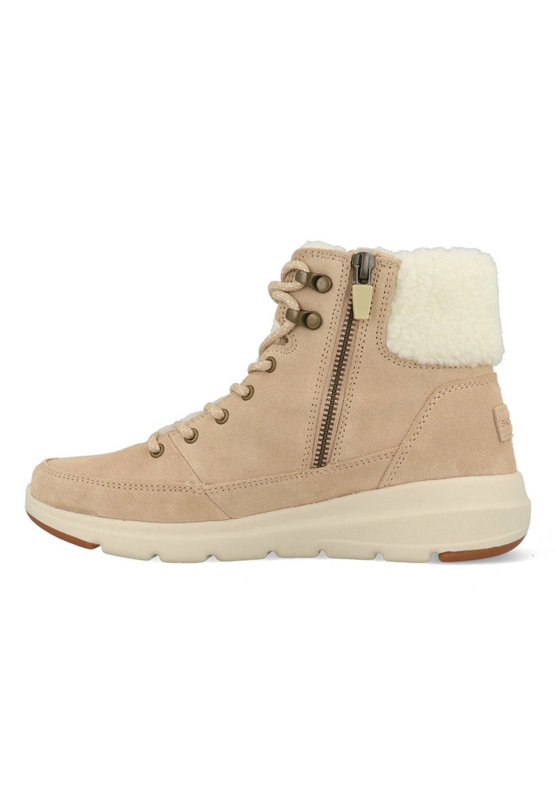 Beige suède enkellaars met zijrits, vetersluiting aan de voorkant, geveerde zool en een witte fleece kraag voor warmte en comfort.