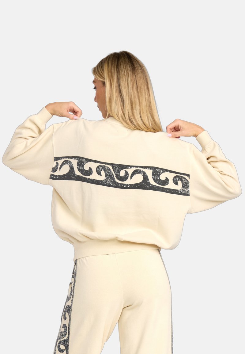 Crème sweatshirt met een brede zwarte golfpatroon over de rug. Heeft een losse pasvorm en ribgebreide manchetten. Zachte stof met een gestructureerde uitstraling.