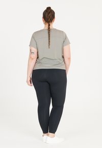 Grå kortärmad skjorta tillsammans med svarta leggings. Skjortan har en avslappnad passform och slät textur; leggingsen är figurnära och stretchiga.