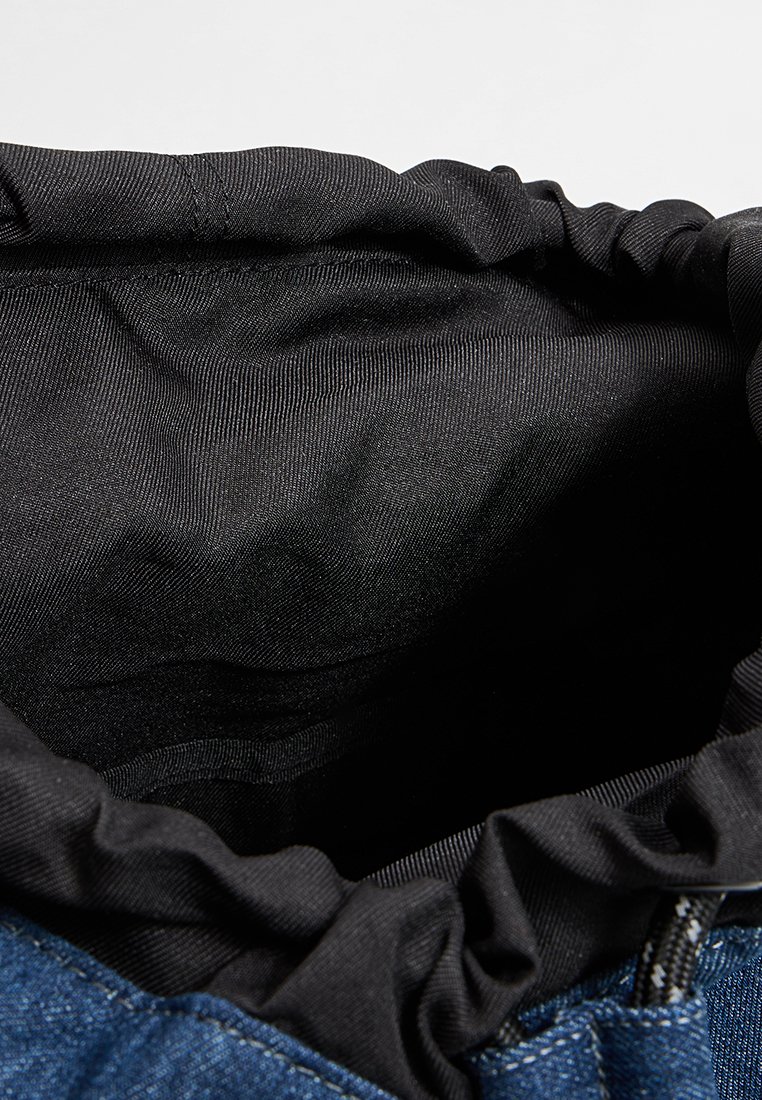 Denim tas met een geplooide zwarte voering, die een ruime binnenkant toont. Kenmerkt zich door een zachte textuur en een strak bovenaan. Zichtbaar metalen onderdelen.