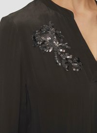 Zwarte blouse met een mandarin kraag, zijdezachte textuur en een versierde sequins bloemen ontwerp op de linkerschouder.