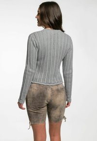 Grau gestrickter Pullover mit gerippter Textur und langen Ärmeln, kombiniert mit beige Shorts im ausgewaschenen Look und seitlichen Details.