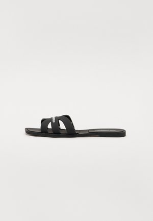Zwarte slide-sandaal met een platte zool en twee brede, kruislings geplaatste banden. Gemaakt van glad materiaal, met een minimalistisch ontwerp en zonder zichtbare patronen.