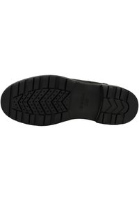 Suela de zapato de goma negra con un diseño de banda de rodadura texturizado que presenta surcos y pequeños agujeros de aire. Logotipo estampado visible cerca del talón.