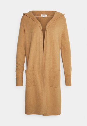 Vaaleanruskea huppari-neule. Varustettu ribbireunuksilla ja taskuilla. Valmistettu pehmeästä, tekstuurisesta materiaalista, jossa on avoin etuosa.