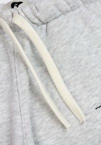 Lichtgrijze sweatpants met een zachte textuur, voorzien van een witte trekkoord en elastische tailleband, met minimale details.