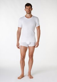 T-shirt bianco in cotone a maniche corte, con colletto rotondo; abbinato a boxer bianchi, texture liscia, design senza cuciture, senza piedi, stile semplice.