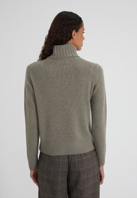 Grüner, gerippter Rollkragenpullover mit langen Ärmeln, gefertigt aus weichem Strickmaterial. Saum und Ärmelbündchen sorgen für einen taillierten Look. Rückansicht.