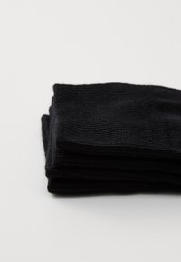 Chaussettes noires empilées soigneusement. Le tissu est côtelé avec une texture douce. Le design est simple, sans motifs ou accents visibles.