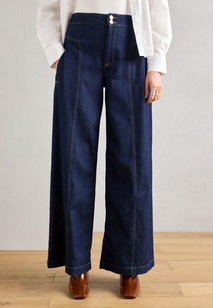 Wide-leg denim trousers in dark blue with contrasting yellow stitching, featuring a high waist and twin button closure at the front.