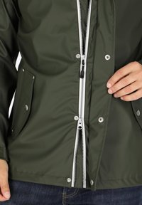Olive green waterproof jacket with a silver zipper, snap buttons, and side pockets, featuring a smooth texture and practical design.